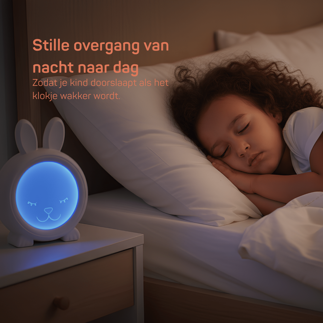 Kind slaapt rustig in bed naast een blauwe slaaptrainer in de vorm van een konijn, stille overgang van nacht naar dag zonder geluid zodat het kind doorslaapt.
